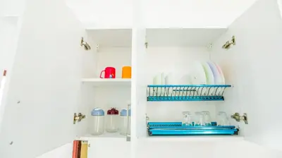 a white kitchen cabinet with plates and utensils at La bonita compound in Hurghada