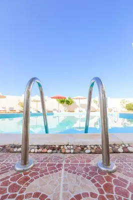 a pool with two metal bars in front of a resort at La bonita compound in Hurghada