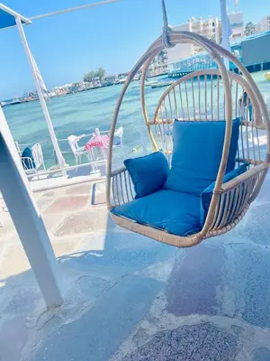 a wicker chair with blue pillows sitting on a porch at Serafy City Center Hostel for Foreigners Adults Only in Hurghada