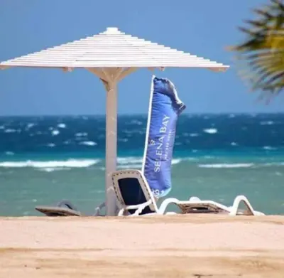 a pair of chairs and an umbrella on the beach at Selina Apartments in Hurghada