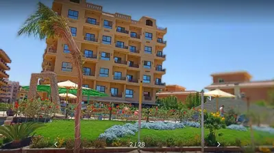a large yellow building with a garden in front of it at Apartment - Sleeps 4 - Pool - Pet friendly in Hurghada