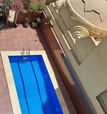 a blue swimming pool on the side of a building at Villa Belzoni in Luxor