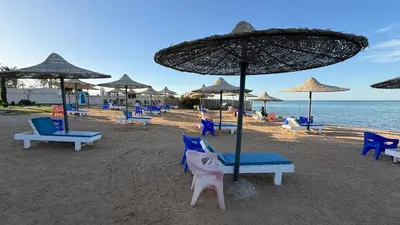 a beach with chairs and umbrellas and the ocean at Casablanca Beach Direct sea view Tow Bedroom Apartment in Hurghada