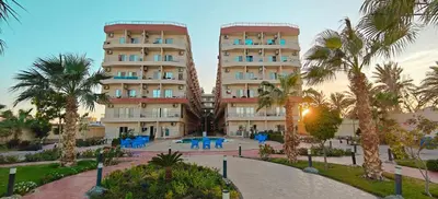 a large apartment building with blue tables and palm trees at Casablanca Beach Direct sea view Tow Bedroom Apartment in Hurghada