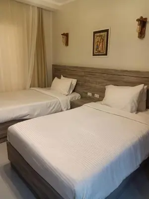 two beds in a hotel room with white sheets at Scandic Resort in Hurghada
