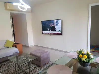 a living room with a couch and a tv on the wall at شقه غرفتين وصاله بالحديقه في فراندا سهل حشيش in Hurghada