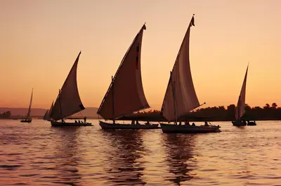 a group of sailboats on the water at sunset at Royal Home Luxor Pool View in Luxor