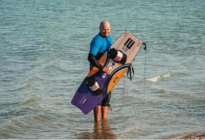 a man is standing in the water with a board at Amazing 2 bedroom Selena Bay Hurghada in Hurghada