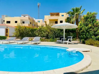 a swimming pool with an umbrella and chairs at Moubark 6 Directly to the swimming pool in Hurghada