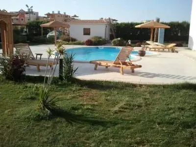 a swimming pool with two chairs and a table at Moubark 6 Directly to the swimming pool in Hurghada
