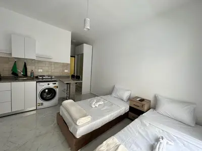 two beds in a room with a kitchen at Уютное место рядом с променадом in Hurghada