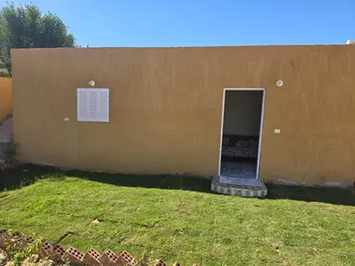 a small building with a door and a grass yard at Moon Adam hostel in ‘Ezbet Abu Ḥabashi
