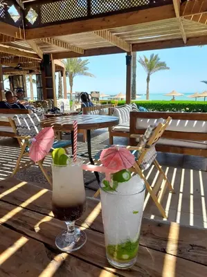 two cocktails sitting on a wooden table on the beach at Palma Resort Hurgáda,8P4J22Q, Hurgada Palma Resort, apartment K75, Al Ismaileya, in Hurghada
