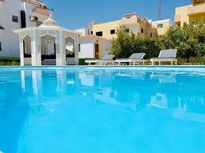 a swimming pool with a gazebo and blue water at Hurghada-Magawish Villa 1 in Hurghada