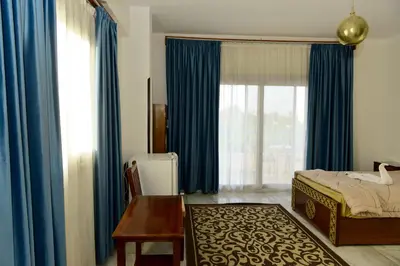 a bedroom with blue curtains and a bed and a table at Flamingo Boutique hotels in Luxor