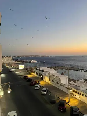 a street with cars parked in a parking lot next to the ocean at BLUE ViEW SUiTES in Hurghada