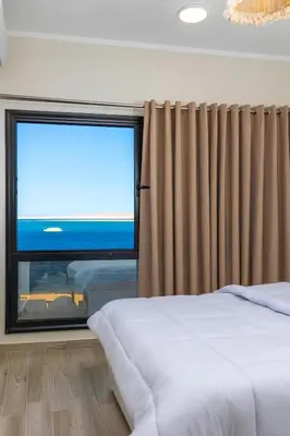 a bedroom with a large window with a large television at BLUE ViEW SUiTES in Hurghada