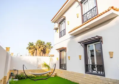 a white house with a hammock in the yard at Royal Home Luxor Nile View in Luxor