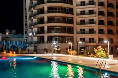 a swimming pool in front of a building at night at Scandic Resort - Mido Chalet in Hurghada