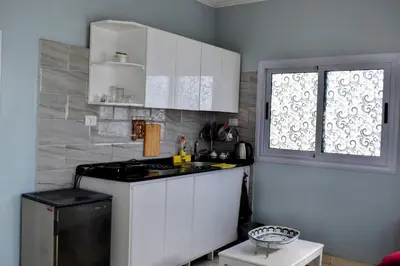 a kitchen with white cabinets and a stove and a window at Villa Rebecca in Luxor