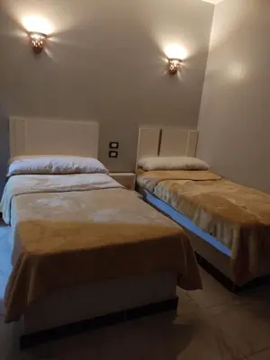 two beds in a room with lights on the wall at Hamo Fathy Nubian House in Aswan