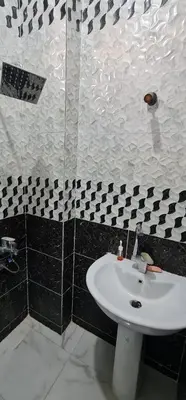 a bathroom with a white sink and black and white tiles at Hamo Fathy Nubian House in Aswan