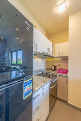 a kitchen with white cabinets and a stainless steel refrigerator at NEW! 2BR Duplex in Tawila, Gouna Private Jacuzzi, Garden, Lagoon & Pool in Hurghada
