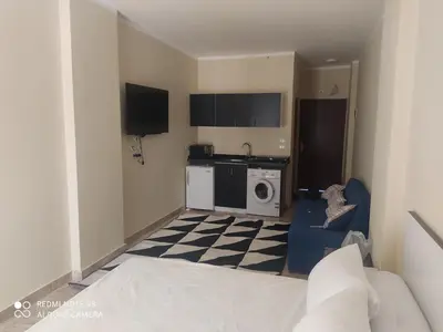 a room with a bed and a kitchen with a washing machine at Magawish District in Hurghada