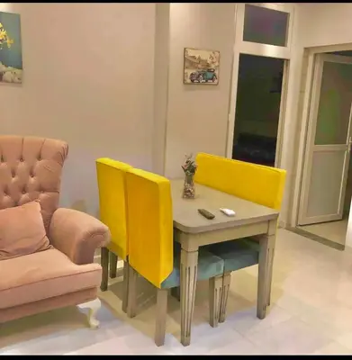 a dining room with yellow chairs and a table and a couch at Sea view Apartment in Hurghada