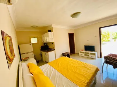 a living room with a yellow bed and a kitchen at One room in a compound with the swimming pool in Hurghada