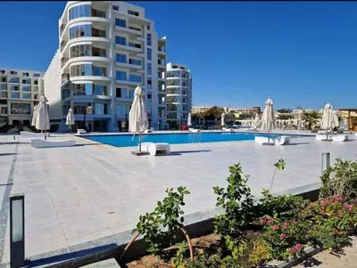 a swimming pool with umbrellas and a building at Scandic Resort Hurghada in Hurghada