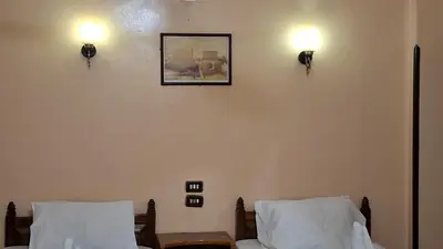 a bedroom with two beds and a picture on the wall at West Bank Guest House in Luxor
