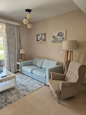a living room with a blue couch and a chair at Mangroovy- 1BR Bleu Ciel in Hurghada