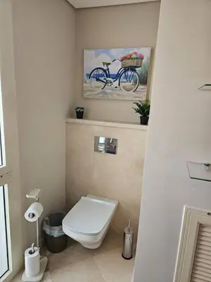 a bathroom with a toilet and a bike painting on the wall at Mangroovy- 1BR Bleu Ciel in Hurghada
