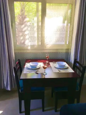 a table with two glasses of wine and a window at Villa Elkoumy Apartments in Luxor