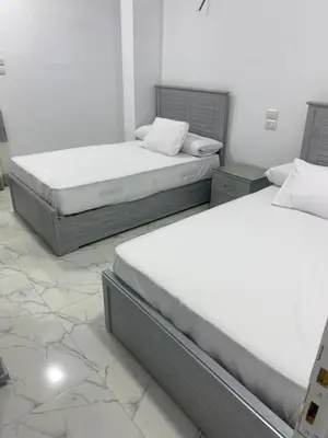 two twin beds in a room with marble floors at Nuba Heart in Aswan