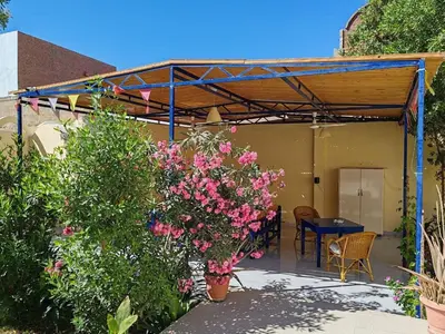 a patio with a table and pink flowers at Villa Bauhaus in Al Aqālitah