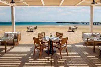 a patio with tables and chairs on the beach at JAZ Elite Amara in Marsa Alam City