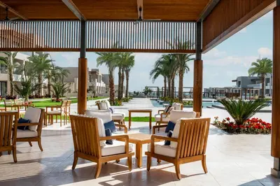 a patio with tables and chairs and a pool at JAZ Elite Amara in Marsa Alam City