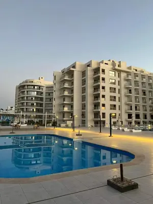 a swimming pool in front of a large apartment building at scandic resort in Hurghada