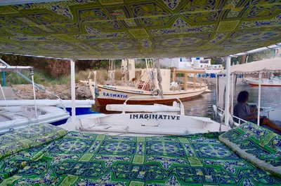 a boat with a bed on the water with two boats at Felucca sailing overnight experience with imaginative felucca aswan in Aswan