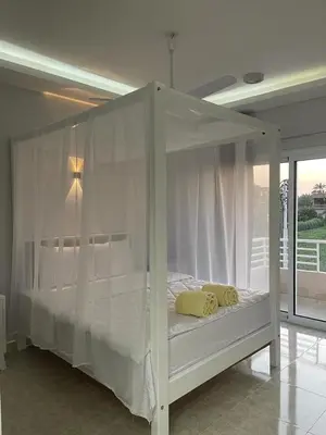 a white canopy bed with yellow pillows on it at Royal Nile Villas - Luxury Nile View Apartment 2 in Luxor