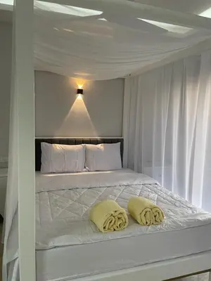 a white bed with two yellow pillows on it at Royal Nile Villas - Luxury Nile View Apartment 2 in Luxor