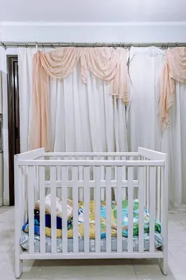a white crib in a room with a curtain at one bedroom apartment in Hurghada