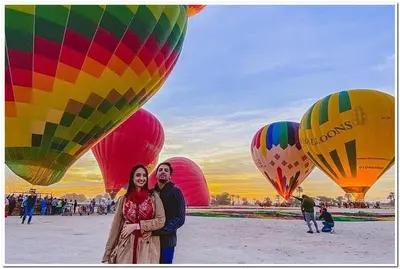 a man and woman standing in front of a group of hot air balloons at Green Palace Garden in Luxor