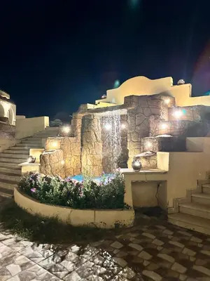 a stone wall with a waterfall and stairs at night at Elphardous Oasis Hotel in Luxor