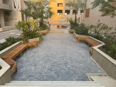 a walkway with benches and trees and a building at Cozy Studio With Private Beach ! in Hurghada