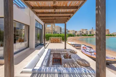 an outdoor patio with tables and boats on the beach at Comfy 3BR Standalone in Tawila, El Gouna. Lagoon & Pool access in Hurghada