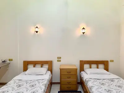 two beds in a room with lights on the wall at Sunset Haven Guesthouse in Luxor