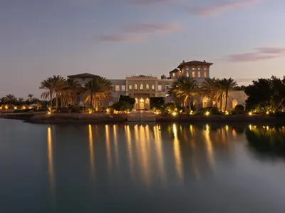 a large building with palm trees in front of a lake at La Maison Bleue El Gouna in Hurghada